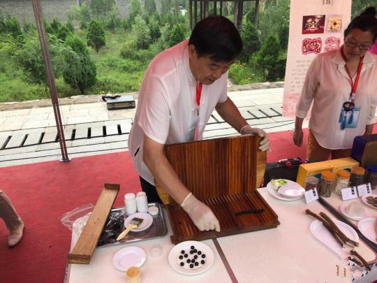 图为开幕式现场的中药炮制技艺展示。